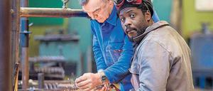 Ein älterer und ein jünger Mann hantieren mit einem Schweißgerät.