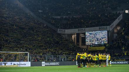 Fußball: Bundesliga, Borussia Dortmund - FSV Mainz 05, 26. Spieltag am 13.03.2016 in Signal Iduna Park, Dortmund (Nordrhein-Westfalen). Dortmunds Fans halten ihre Schals in die Höhe und singen "You never walk alone" für einen Fan, der während des Spiels an einem Herzinfarkt gestorben war, während die BVB-Spieler Arm in Arm vor der Südtribüne stehen. Foto: Bernd Thissen/dpa (zu dpa "Dortmunder OK-Chef nach Todesfall im Stadion: «Es war sehr bewegend» " am 14.03.2016) +++(c) dpa - Bildfunk+++