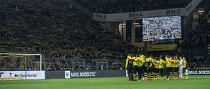 Fußball: Bundesliga, Borussia Dortmund - FSV Mainz 05, 26. Spieltag am 13.03.2016 in Signal Iduna Park, Dortmund (Nordrhein-Westfalen). Dortmunds Fans halten ihre Schals in die Höhe und singen "You never walk alone" für einen Fan, der während des Spiels an einem Herzinfarkt gestorben war, während die BVB-Spieler Arm in Arm vor der Südtribüne stehen. Foto: Bernd Thissen/dpa (zu dpa "Dortmunder OK-Chef nach Todesfall im Stadion: «Es war sehr bewegend» " am 14.03.2016) +++(c) dpa - Bildfunk+++