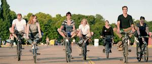 Teilnehmer eines Kurses im YogaCycling fahren auf dem Tempelhofes Feld in Berlin Fahrrad im Yogasitz.