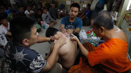 Ein Mönch in Thailand setzt zum Tattoo-Stich an.