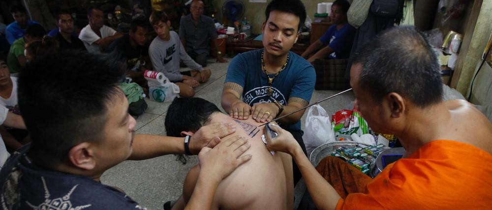 Ein Mönch in Thailand setzt zum Tattoo-Stich an. 