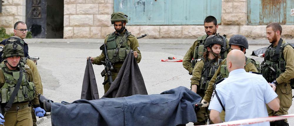 Israelische Soldaten tragen den getöteten Palästinenser weg.