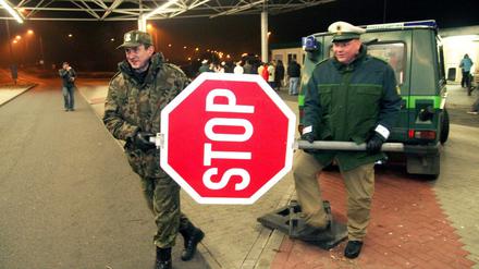 Ein deutscher und ein polnischer Polizist räumen am Grenzübergang Forst-Sacro gemeinsam ein Stoppschild zur Seite. Das war Ende 2007, zum Beitritt Polens zum Schengen-Raum.