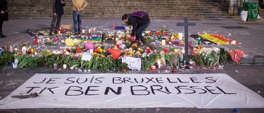 Ein Passant zündet am 23.03.2016 in Brüssel vor der Börse am Place de la Bourse hinter einem Banner mit der Aufschrift "Je suis Bruxelles Ik ben Brussel" eine Kerze an.