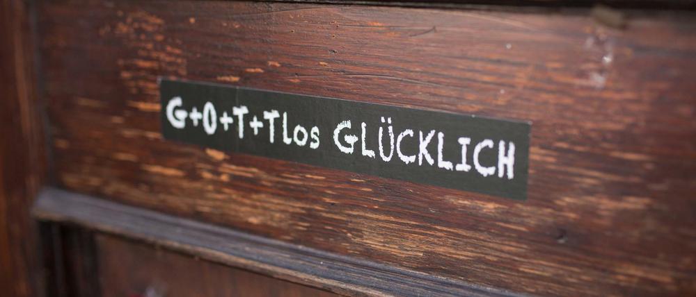 Ein Aufkleber mit der Aufschrift "Gottlos Glücklich" klebt am 17.03.2016 in Bochum vor dem Haus Dahlhoff, dem "sozialen Zentrum" an der Eingangstür. Am 25. März möchte die Initiative ein Filmfest gegen das Feiertagsgesetz in Nordrhein-Westfalen starten und den Film "Das Leben des Brian" zeigen.
