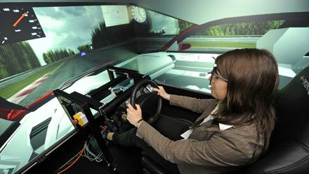Eine junge Frau sitzt am Steuer eines Fahrsimulators.