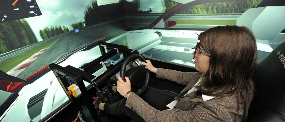 Eine junge Frau sitzt am Steuer eines Fahrsimulators.