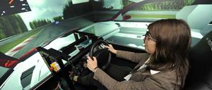 Eine junge Frau sitzt am Steuer eines Fahrsimulators.