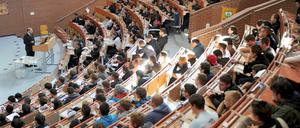 Studierende sitzen im Hörsaal und blicken nach vorne zu ihrem Professor.