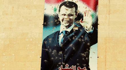 Ein beschossenes Plakat von Baschar al Assad.