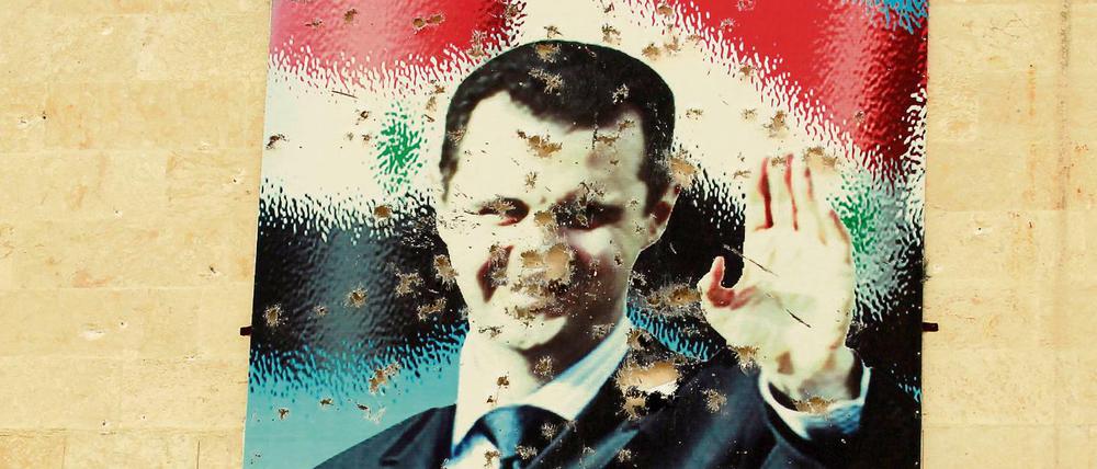Ein beschossenes Plakat von Baschar al Assad.