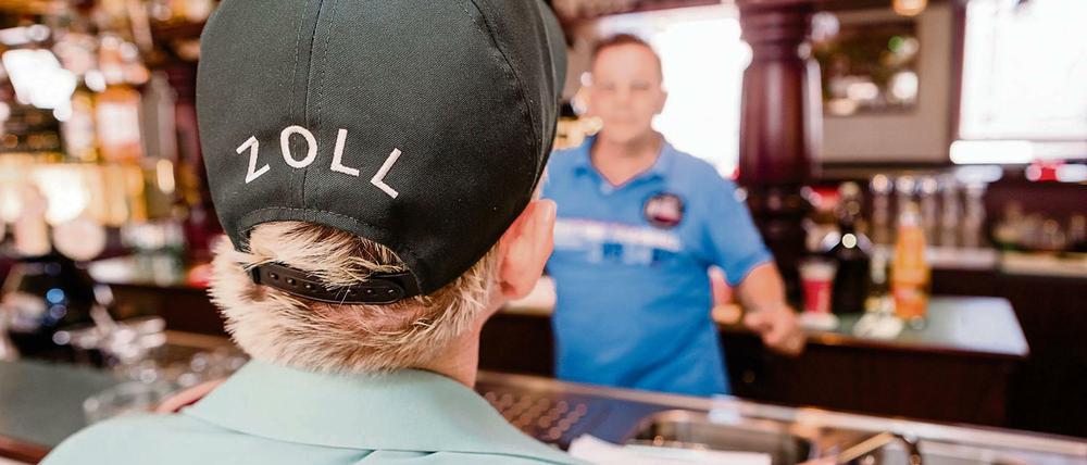 Eine Zollbeamtin nimmt die Daten eines Mitarbeiters auf, um anschließend überprüfen zu können, ob hier der gesetzlich vorgeschriebene Mindestlohn durch den Arbeitgeber gezahlt wird.