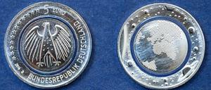 Die neue deutsche Fünf-Euro-Münze "Blauer Planet Erde". Die sogenannte "Tri-Material-Coin" hat in der Mitte einen durchsichtigen, blau schimmernden Ring aus Kunststoff, der Euromünzen in Zukunft besser vor Fälschungen schützen soll.