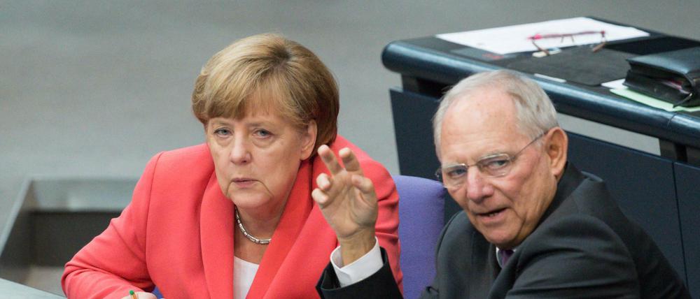 Bundeskanzlerin Angela Merkel (l, CDU) und Bundesfinanzminister Wolfgang Schäuble (CDU) unterhalten sich im Plenum des Deutschen Bundestages. 