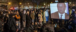 Teilnehmer der "Nuit debout"-Kundgebung verfolgen auf dem Pariser Platz der Republik das TV-Interview von Präsident Hollande.