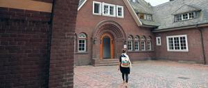 Eine junge Frau geht über den Innenhof eines historischen Gebäudes auf eine Tür zu.