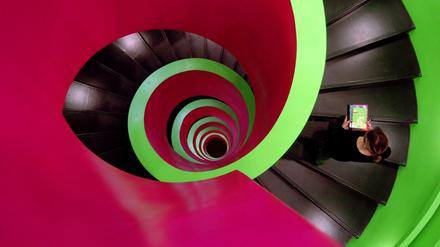 Eine Frau geht auf einer zweifarbig gestalteten Wendeltreppe nach oben.