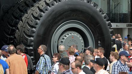Messebesucher stehen auf der Baumaschinenmesse Bauma in München vor den Rädern eines "Dumpers"
