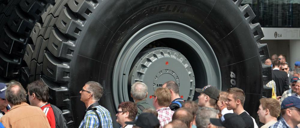 Messebesucher stehen auf der Baumaschinenmesse Bauma in München vor den Rädern eines "Dumpers"