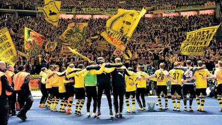 Können sich wieder in den Armen liegen. Die Dortmunder Profis lassen sich von ihren Fans für ihre Vorstellung im Olympiastadion feiern. Foto: dpa/Kastl