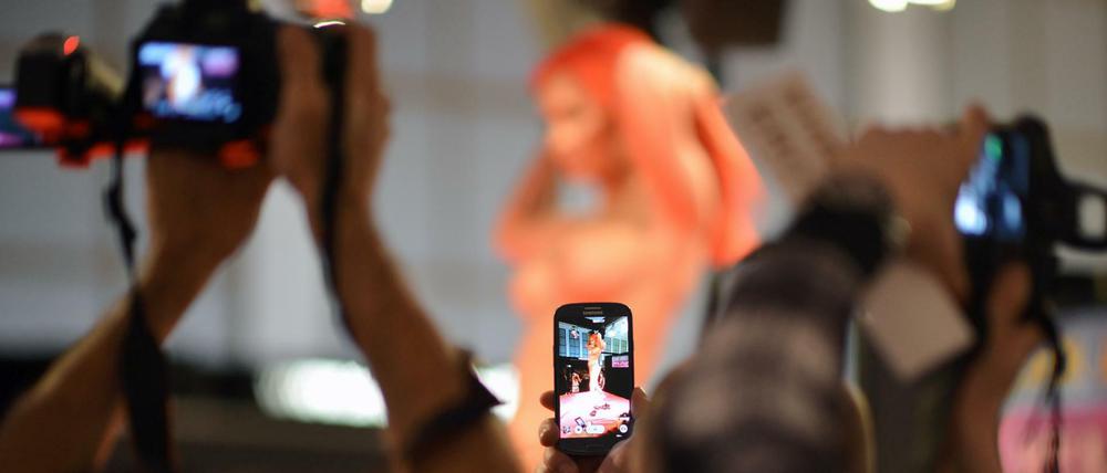 Besucher filmen und fotografieren während der Erotik-Messe «Venus» in Berlin die Vorführungen einer Frau. 