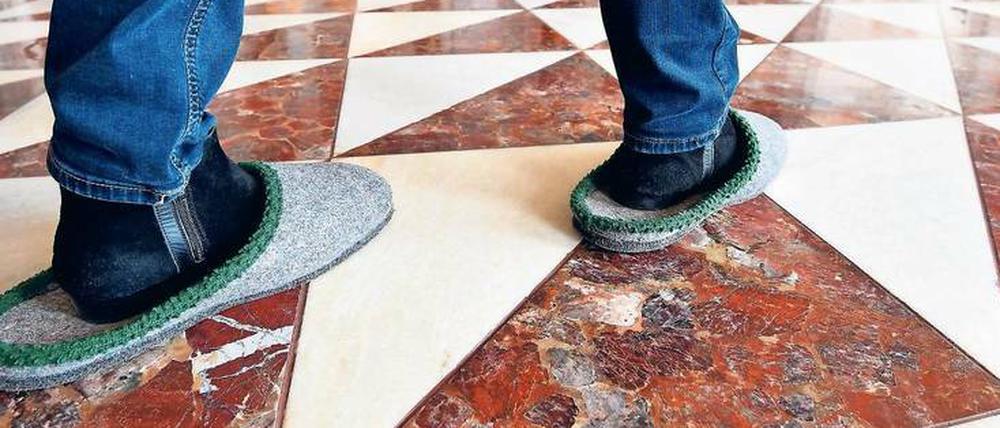 Pantoffeldruck. Eine Besucherin geht in den Neuen Kammern in Potsdam durch die Ausstellung. Der Schutz für die Böden ist umstritten.