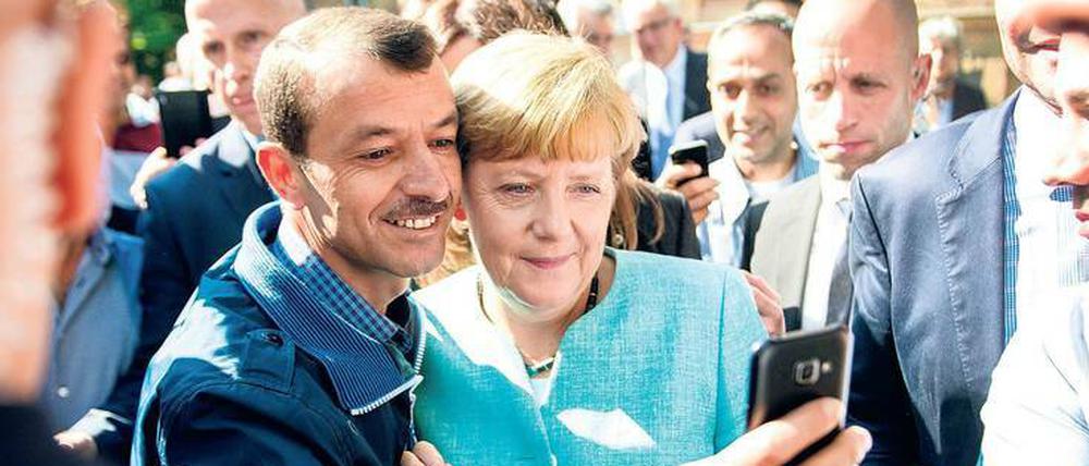 Angela Merkel und ein Flüchtling beim „größten Sozialexperiment Europas seit der Russischen Revolution“ (Sarrazin).