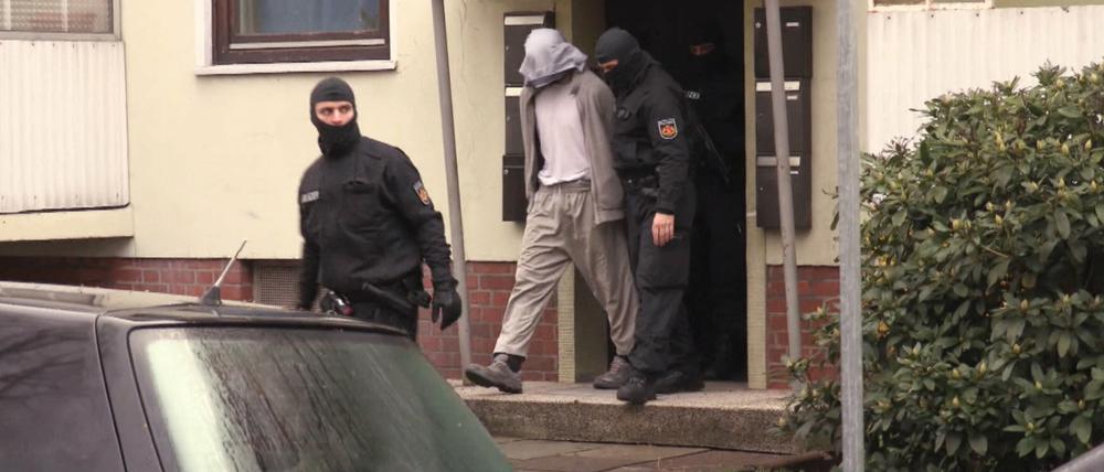 Polizisten führen am Dienstag in Bremen einen Mann aus einem Haus. Die Polizei hat mehrere Wohnungen und Geschäfte von Salafisten in Bremen durchsucht.