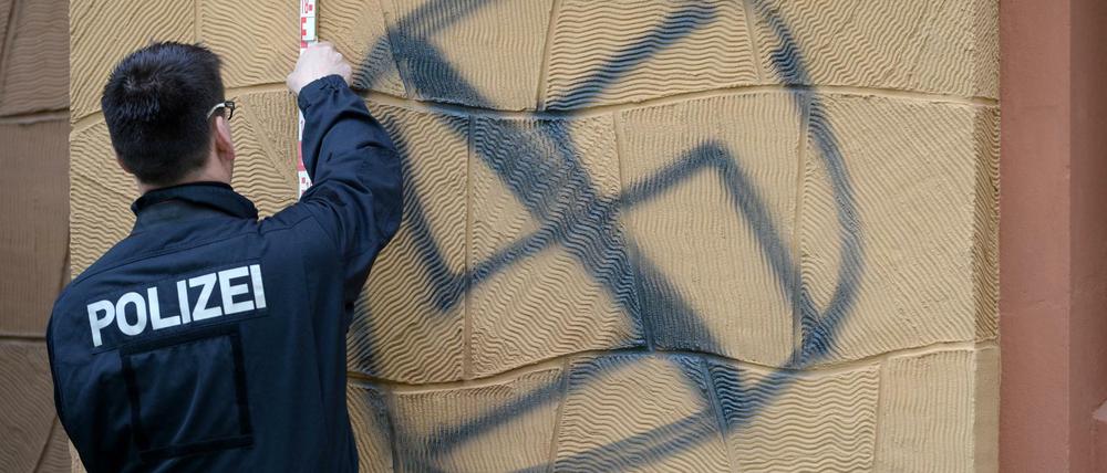 Ein Polizist sichert aan der Fassade des Wohnhauses von AfD-Vize Alexander Gauland Spuren an einem gesprühten Hakenkreuz.