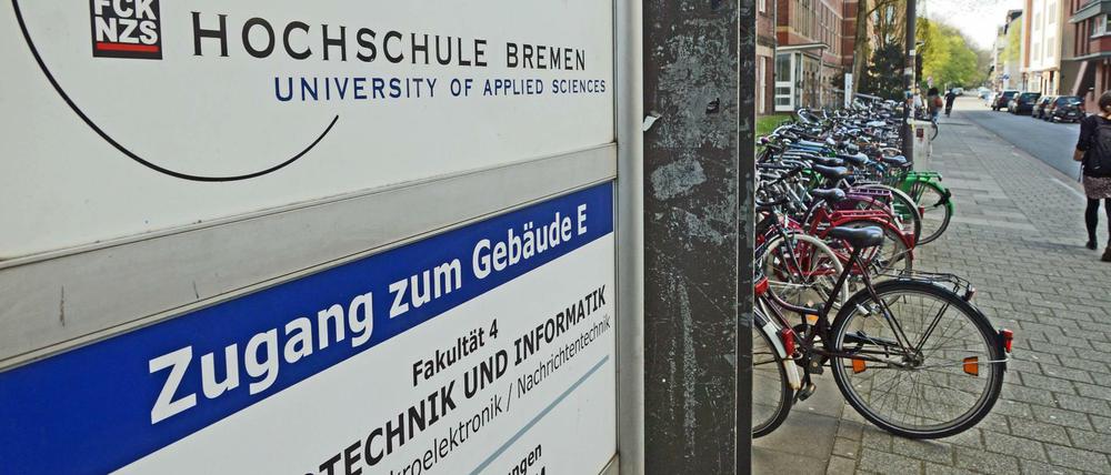 Ein Hinweisschild weist ein Hochschulgebäude als Fakultät für Elektrotechnik und Informatik aus, auf dem Gehweg davor ist eine Passantin zu sehen.