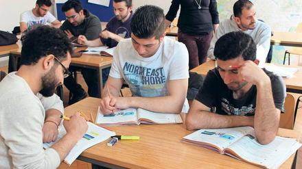 Junge Männer sitzen in einem Klassenraum an Tischen und Arbeiten in Lehrbüchern.