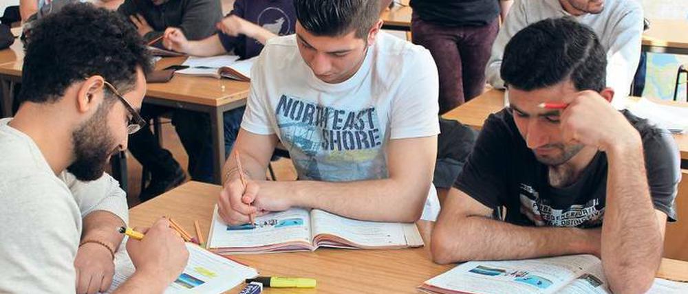 Junge Männer sitzen in einem Klassenraum an Tischen und Arbeiten in Lehrbüchern.