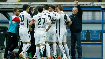 Freiburgs Spieler und Trainer Christian Streich (r) feiern das 1:0 gegen Paderborn.