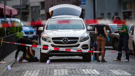 Mitarbeiter der Spurensicherung untersuchen den Tatort am weißen Mercedes-Geländewagen in Frankfurt am Main. 