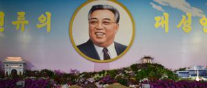 Eine Frau in Uniform vor einem Portrait von Kim Il Sung in Nordkorea.