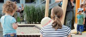 Kita-Personal spielt mit Kindern auf einem Spielplatz.