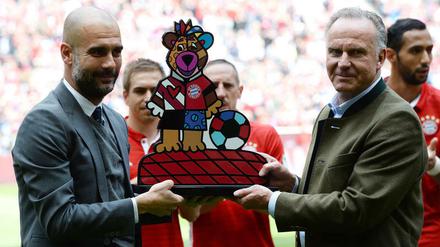 Ist das wirklich euer Ernst? Pep Guardiola wird von Karl-Heinz Rummenigge eindrucksvoll beschenkt.