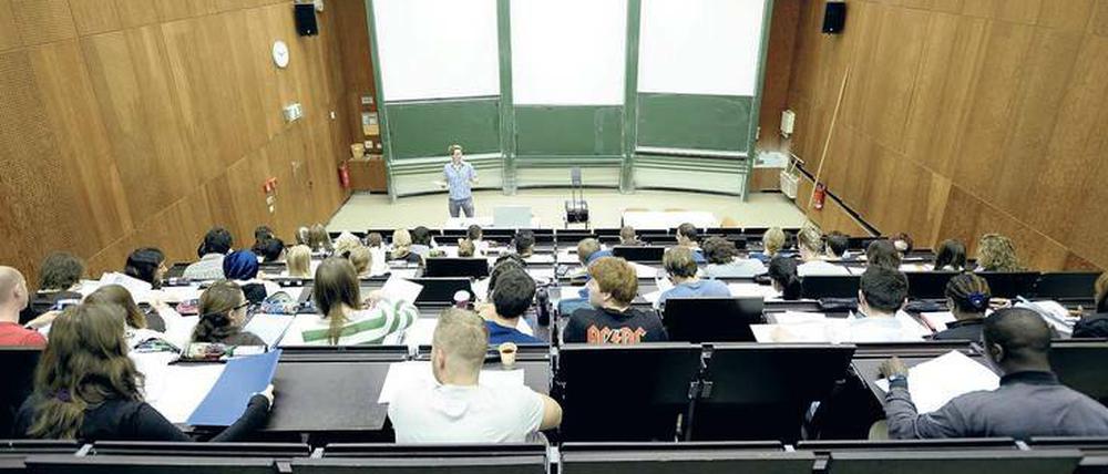 Ein junger Dozent steht vor Studierenden, die in einem Hörsaal sitzen.