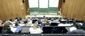 Ein junger Dozent steht vor Studierenden, die in einem Hörsaal sitzen.