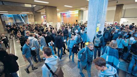 Viele junge Frauen und Männer gehen durch das Foyer einer Universität.
