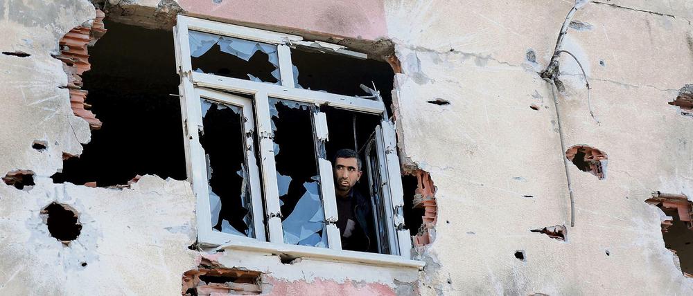 Ein Mann blickt aus einem Gebäude in Diyarbakir, das bei Kämpfen zwischen türkischen Sicherheitskräften und militanten Kurden stark beschädigt worden ist.