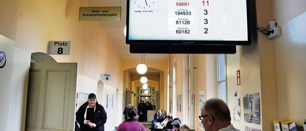 Ein Monitor mit roten Zahlen und schwarzen Zahlen, und geduldige Terminkunden, die auf ihre Chance warten: Berliner Bürgeramt, hier im Bezirk Pankow.