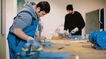 Der afghanische Flüchtling Sha Kah Ahmadi (l.) und der indischen Flüchtling Singh Satwinder feilen in der Fortbildungsakademie der Wirtschaft (FAW) in Dresden (Sachen) an Metallwerkstücken.