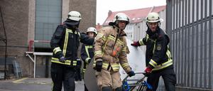 Feuerwehrleute transportieren den Gefahrgutbehälter mit der explodierten Batterie von der Volksbühne ab.