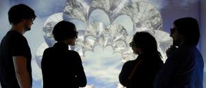 Junge Männer und Frauen stehen vor einer virtuell generierten Grafik.