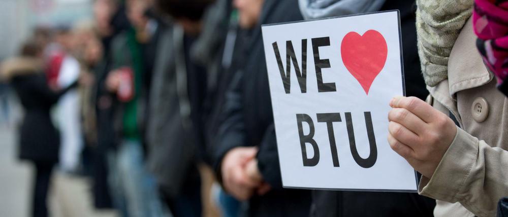 Eine junge Frau hält ein Schild mit der Aufschrift We love BTU in der Hand.