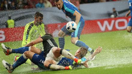 Der Deutsche Mario Götze (vorn) rutscht im Zweikampf mit dem Slowaken Martin Skrtel durch eine Pfütze.