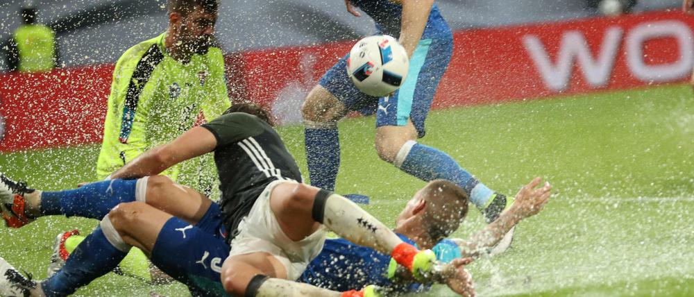 Der Deutsche Mario Götze (vorn) rutscht im Zweikampf mit dem Slowaken Martin Skrtel durch eine Pfütze.