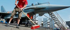 Ein Mann fegt auf der Internationalen Luft- und Raumfahrtausstellung in Schönefeld, vor einem Eurofighter das Ausstellungsgelände.